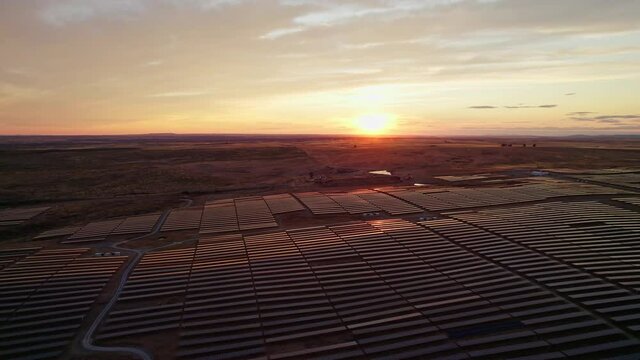 Massive solar plant at sunset. Hundreds of moving solar panels to provide clean energy. Talasol. Drone going backwards and up, revealing the solar plant.