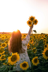 Woman holding sunflowers during a sunset