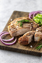 Grilled pork steak on a serving board on the gray background