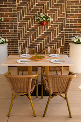 Luxurious restaurant table with rattan chairs. Pizza and four plates on the table