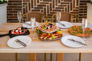 Luxurious table in the restaurant. On the table is a plate with seafood, pizza, vegetable and fruit salad