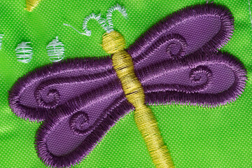 purple machine embroidered dragonfly on a cheap nylon garden banner close up
