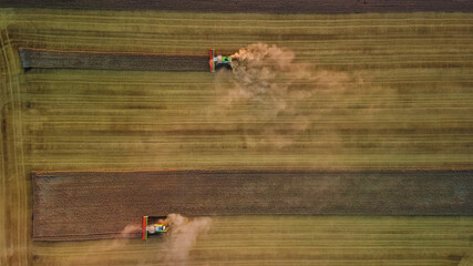 Aerial view of modern harvesters working in a field. Combines harvest wheat in the field at sunset.