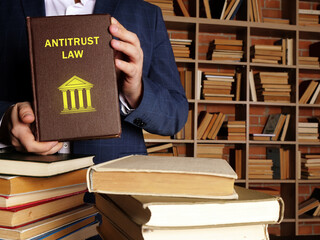 Lawyer holds ANTITRUST LAW book. Competition law is known as antitrust law in the United States...