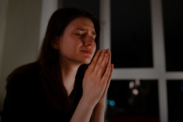 Young woman praying and crying at night