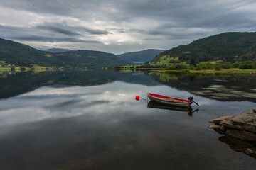 A lonely red boat in the lake against the background of the mountains. Norway.