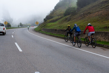 Ciclistas montando en bicicleta a la orilla de la carretera en las motañas en un día nublado