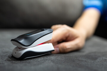 Using a digital oximeter to measuring oxygen saturation and blood pulse at human finger. Healthcare medical equipment. Partial selective focus at the device's part.