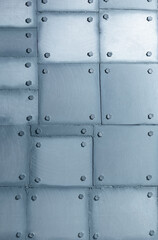 Background of silvery wall made of polyethylene foam sheets imitating metal with rivets.