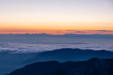 Fototapeta na wymiar 令和３年７月の白山御前峰から眺める日の出前の雲海に浮かぶ北アルプス連峰のシルエット