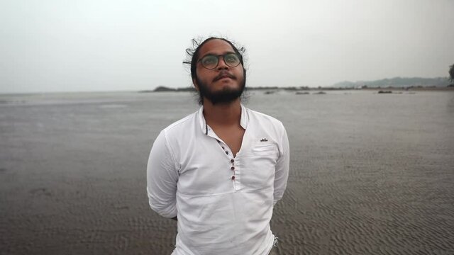 indian long hair boy walking on beach gorai india vivekanand ingle  talking on phone sand sea front.