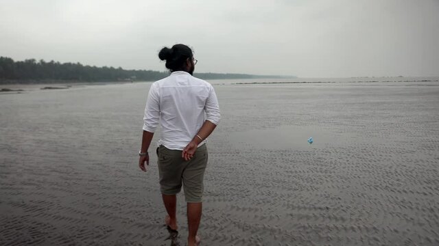 indian long hair boy walking on beach gorai india vivekanand ingle  talking on phone sand sea.