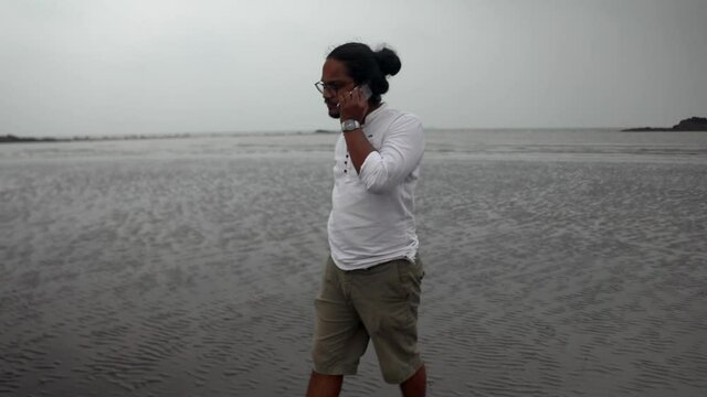 indian long hair boy walking on beach gorai india vivekanand ingle  talking on phone
