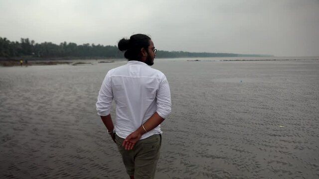 indian long hair boy walking on beach gorai india vivekanand ingle  talking on phone sand.