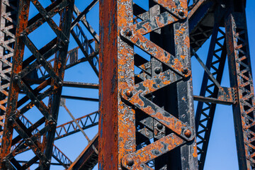 Rusty metal beams for train tracks bridge with blue sky