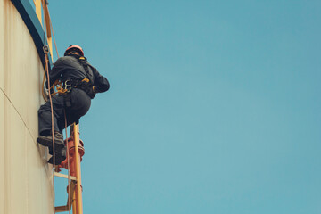 Male worker rope access height safety inspection of thickness storage oil and gas tank
