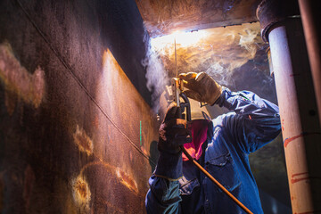 Welding male worker metal arc is part in machinery tank nozzle pipeline construction tank oil inside confined spaces.