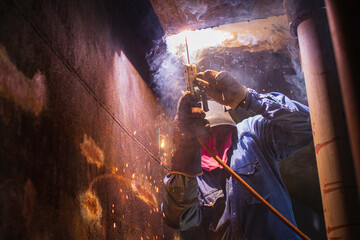 Welding male worker metal arc is part in machinery tank nozzle pipeline construction tank oil inside confined spaces.