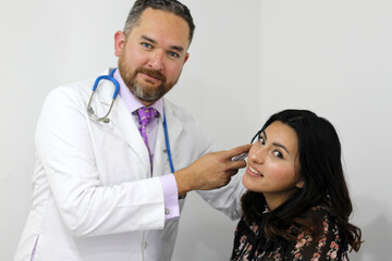 Doctor examining his latin woman patient checking ear, eyes and body reflexes, regular examination
