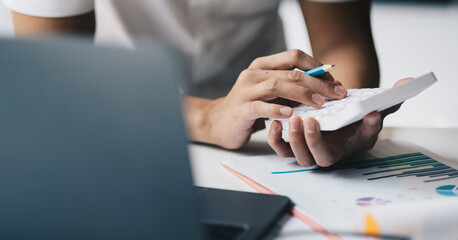 Close up hand of accounting man working on workplace desk in office use calculator calculates monthly expenses, taxes, check bank account balance