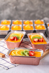 Fresh orange cake topping with orange pulp kiwi fruit and strawberry in foil cup.
