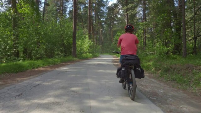 Two teenagers travel on bicycles. Young men on bicycles with cycling backpacks ride along a picturesque forest road.