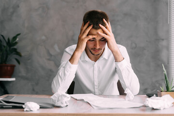 Portrait of businessman man with headache sitting in company office. Solving financial problems....