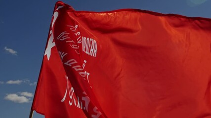 Red USSR flag in slow motion over the blue sky with army squad name from world war ii