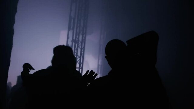 Ravers in a dark club with bald head dancing to the camera weird and laser lights on a scene