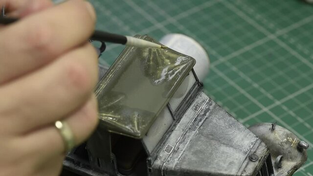 Scale Modeling. Weathering on 1:35 of German 8ton Semi Track plastic model. Close up. A man creates smudges on the roof of the cab of a military vehicle.