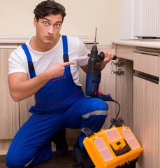 Young repairman working at the kitchen