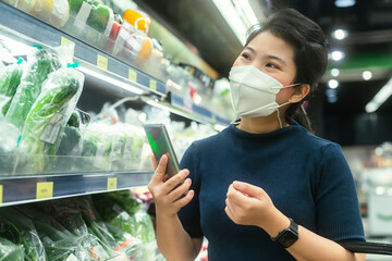young adult asian female woman wearing protective face mask hand choosing fresh product or consumer...