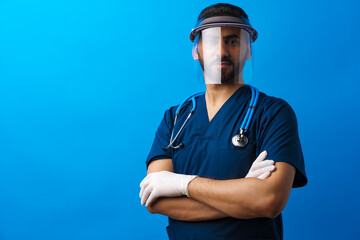 Young arab male doctor standing against blue background