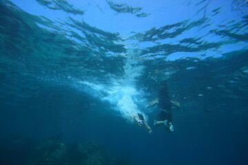 Fototapeta na wymiar underwater photo of man diving into the refreshing clear blue ocean