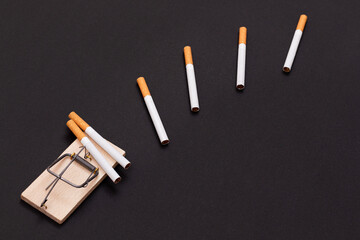 Tobacco Addiction and the World Corporation's Trap - Cigarettes in Wooden Mousetrap on Black Background