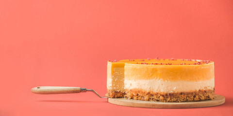 Cheesecake cut with yellow mango mash layer on the red background