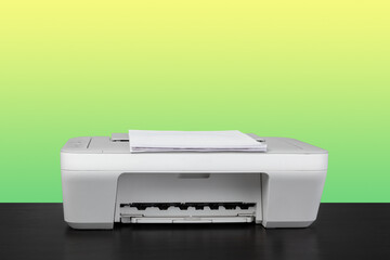 Home laser printer on desk against green background