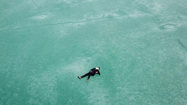 4K on Asian man walking on ice.  Blue Ice surface of Frozen Lake from drone aerial view at Pangong Lake or Pangong Tso, Tso moriri &ndash; Nubra, India. Abstract concept of Cold winter, peaceful and freedom