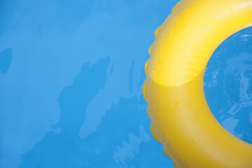Detail of yellow inflatable ring floating in swimming pool in sunny day. Top view.