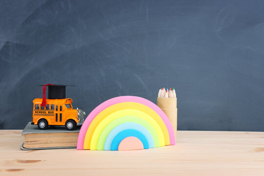 education and back to school concept. yellow bus, graduation hat and pencils over wooden desk