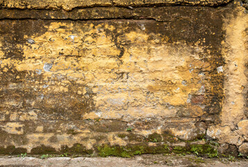 Weathered brick texture painted with yellow paint, aged and rusty wall, pattern.