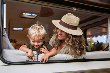 Parent and child in camper van spend time together playing and laughing. Carefree young mother...