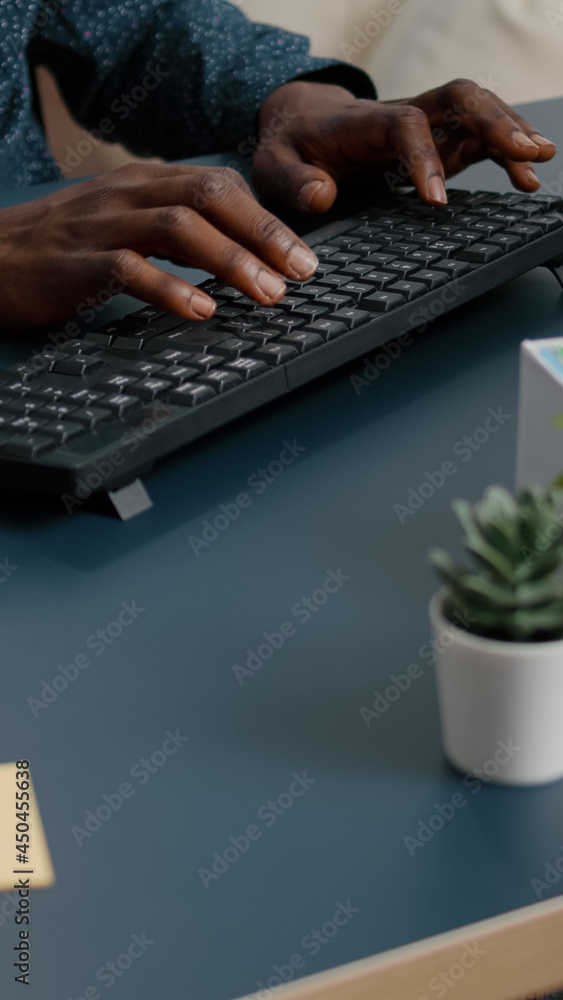 Aufkleber top view of black man african american hands typing on computer keybord on a blue desk. remote worke