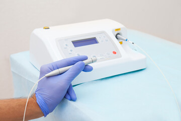 Female hand of dentist in blue gloves holding ultrasonic teeth cleaning machine removing calculus and plaque. Oral hygiene and human teeth treatment concept