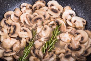 Cooking vegan mushroom ragout with rosemary in a pan, close-up