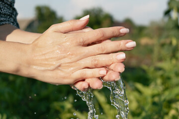 female hands in water on the background of nature