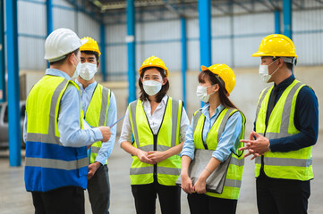 The factory employee consists of engineers, foreman, technicians, and related department staff. Wear a mask, hard hat, and vest. meeting before starting work inside the warehouse. Teamwork concept.