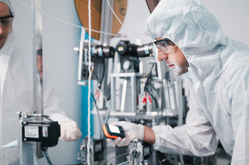 Two scientists wearing uniform protection. Check the manufacturing process face masks. With machinery in a laboratory at industry plants. The concept for security and protection coronavirus covid-19.