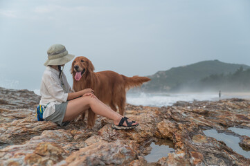 Golden Retriever and owner on the rock by the sea