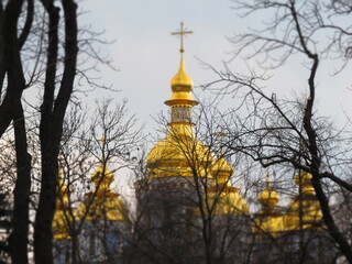 Złote kopuły cerkwi w Kijowie zimą na tle drzew, Ukraina
